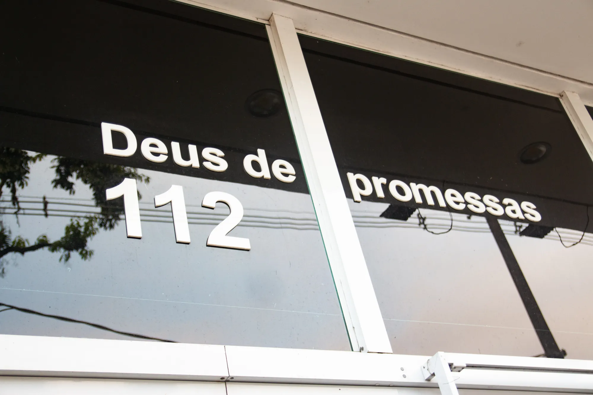 Detalhe da fachada com a frase 'Deus de promessas' e o número 112